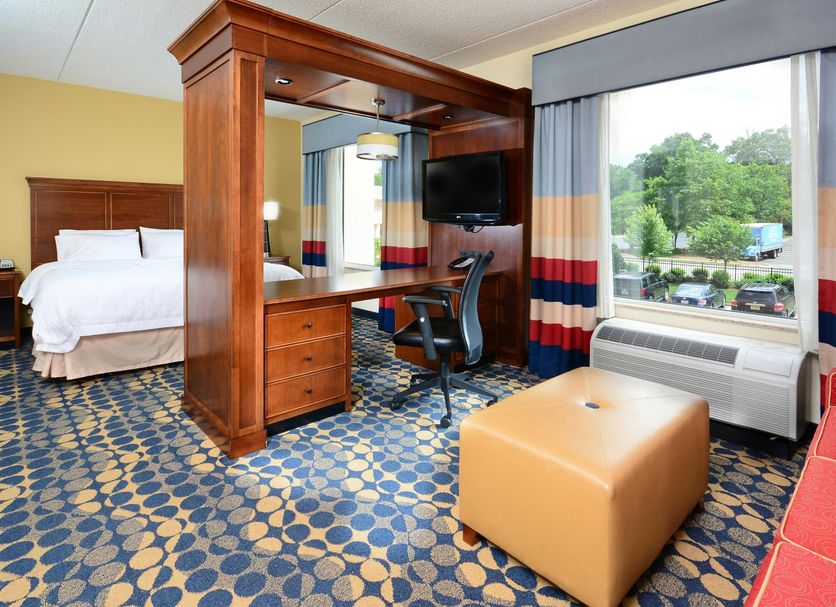 Hampton Inn & Suites Durham/North I-85 guest room with desk, bed, window view, and ottoman in Durham