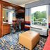 Hampton Inn & Suites Durham/North I-85 guest room with desk, bed, window view, and ottoman in Durham