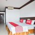 OYO 389 Sira Boutique Residence in Patong, simple hotel room with bed, desk, chair and wall-mounted TV.