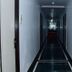 The Rass Kanpur hallway with white walls, dark floor tiles and ceiling lights