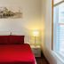 Boston Lodge and Suites in Boston room with red bedspread, twin bedside lamps, and window view