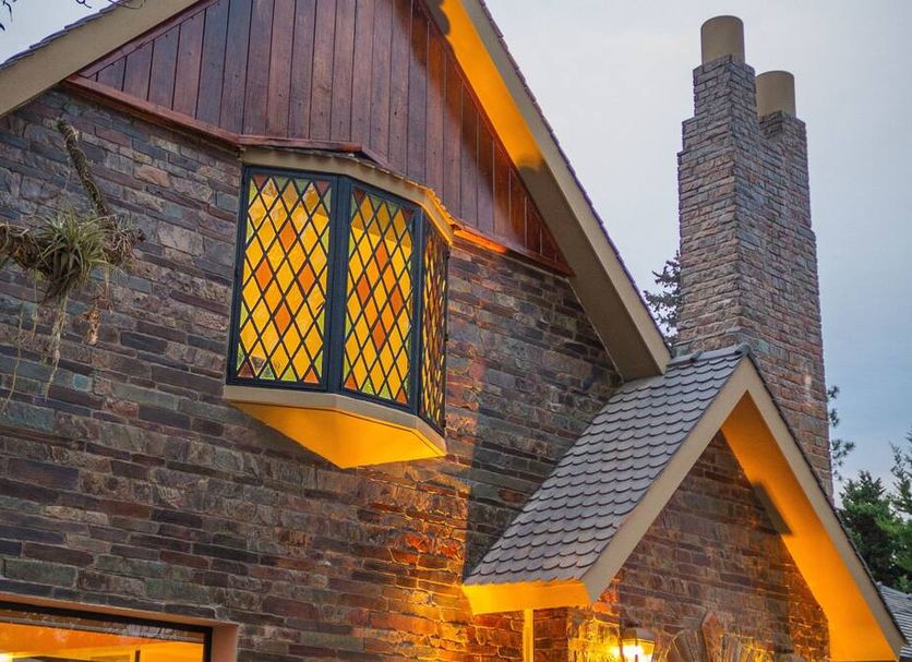 Howard Johnson Hotel Yerba Buena stone exterior with lit bay window and chimney