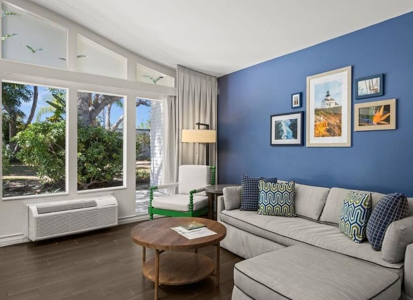 Paradise Point Resort & Spa San Diego room with blue accent wall, gray sofa, and garden-view windows