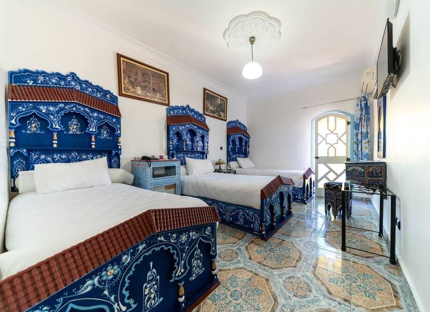Moroccan House Marrakech room with ornate blue beds, patterned tile floor, and small desk