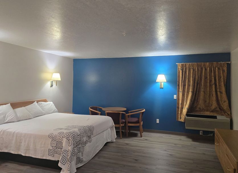 Economy Inn & Suites Nephi guest room with king bed, blue accent wall, table, chairs and window AC