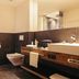 Hotel Kirchenwirt in Kaunertal bathroom with wall-mounted toilet, large sink, and glass shower enclosure