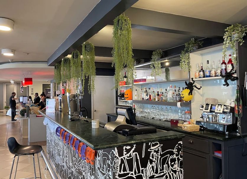 Nobile Inn Santiago hotel bar with hanging greenery, black counter, stools, and shelves of bottles