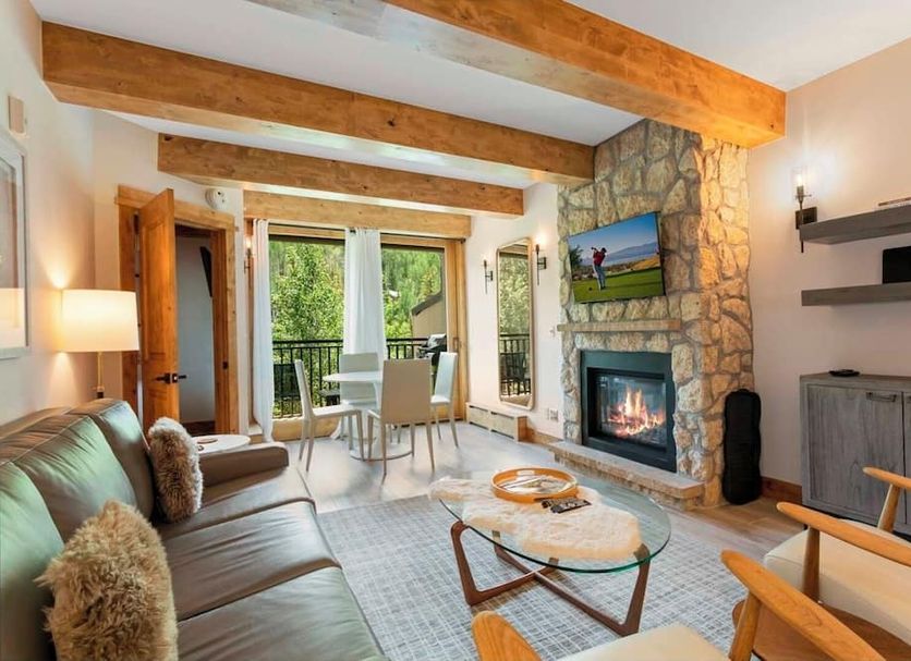 Antlers at Vail living room with stone fireplace, leather sofa, dining area and mountain-view balcony