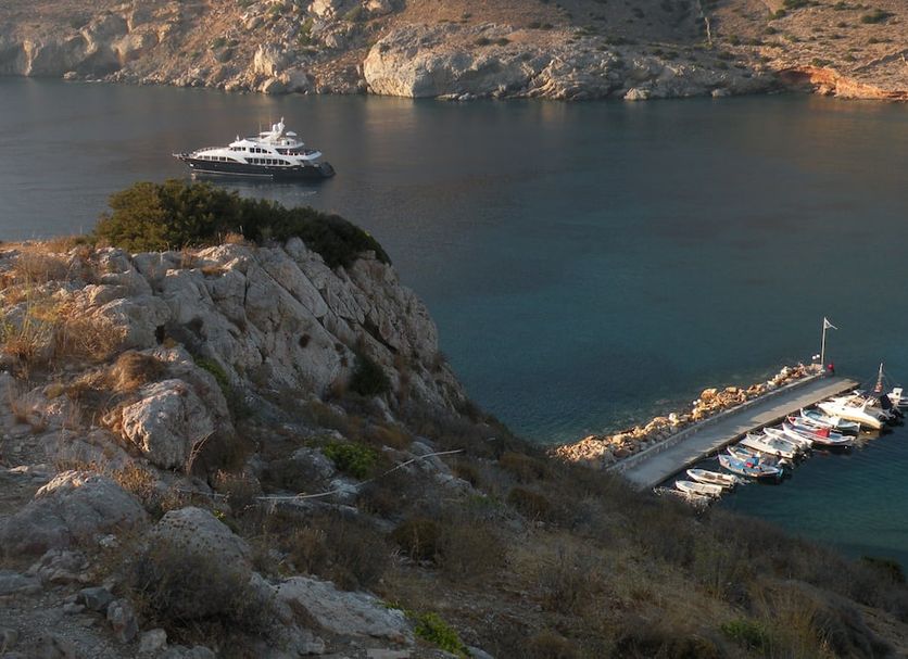 Maistrali, Galissas: rocky seaside cove with yacht moored by a small pier