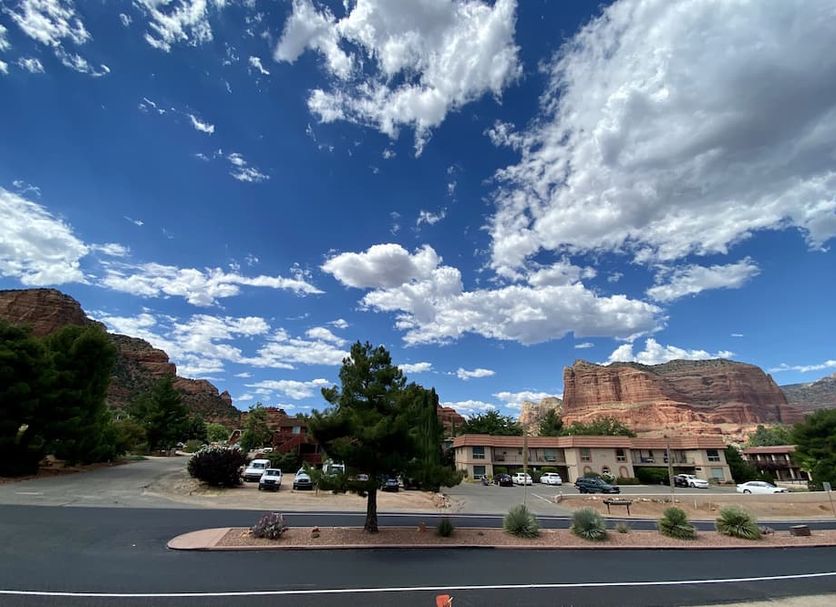 Sedona Village Lodge in Sedona with red rock cliffs, blue sky, and a roadside lodge exterior