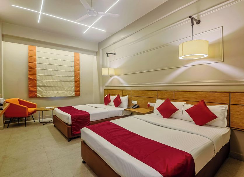 Max Hotels Prayagraj guest room with two beds, red accents and hanging pendant lights