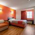 Motel 6 El Paso - Southeast guest room with bed, sofa, orange accent wall and window