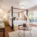 Hotel La Plantacion in Finestrat: elegant bedroom with canopy bed, patio doors, and mountain view