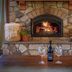 Franziska Haus, Dundee: stone fireplace with a burning fire and wine glasses on a wooden table