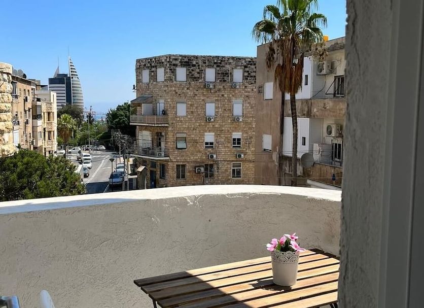 Balcony view from Eden Hotel in Haifa overlooking city buildings, palm trees, and a glimpse of the sea