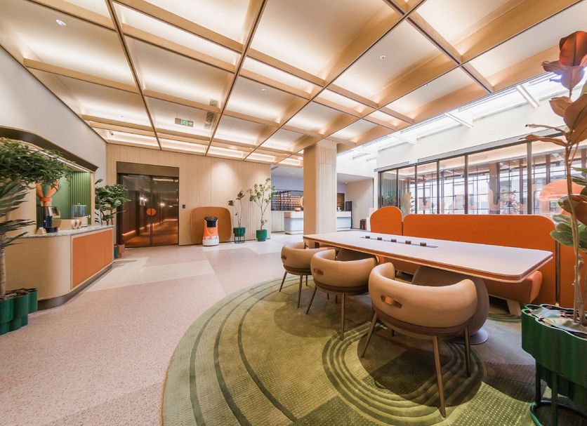Orange Hotel Beijing Tianning Temple lobby with orange seating, plants and skylit ceiling in Beijing
