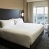 Residence Inn by Marriott Montreal Airport guest room with king bed, city view balcony, chair and wall TV
