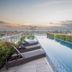 Nims Hotel Seminyak in Kuta, rooftop infinity pool with loungers and city views at sunset