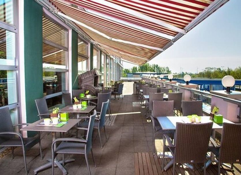 Hotel Nordraum in Bremen: outdoor terrace dining with striped awning and rows of tables overlooking the pool