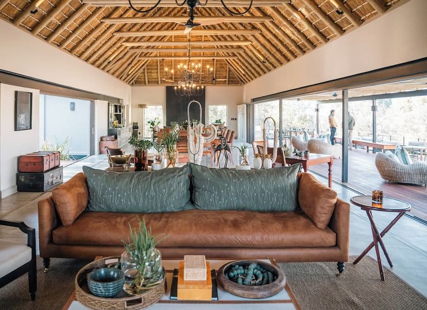 Simbambili Game Lodge in Phungwe, lounge with leather sofa, thatched ceiling and open patio views