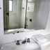 La Defense Apart Hotel bathroom sink and mirror with tiled shower in Montes Claros