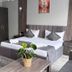 Kausar Hotel Bishkek guest room with twin beds, wardrobe, rug, and potted plant