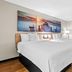 Days Inn by Wyndham Jacksonville NC room with two beds, ocean pier wall art and wood flooring in Jacksonville