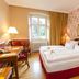 Klosterhotel Wöltingerode in Vienenburg: cozy guest room with twin beds, desk, lamps, and floral wallpaper