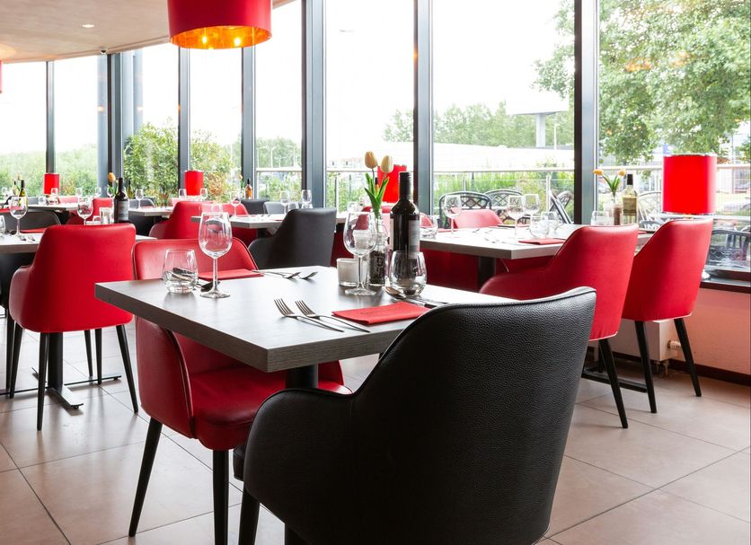 Bastion Hotel Barendrecht restaurant with red chairs and large windows in Barendrecht