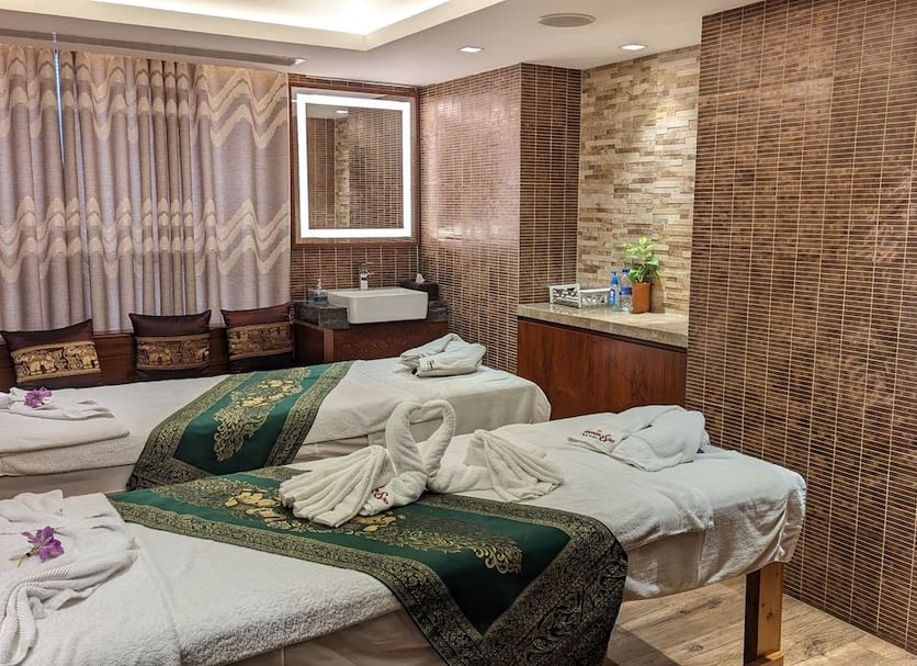 The Peninsula Chittagong Limited spa treatment room with twin massage beds and woven wall panels