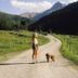 Hotel Geisler Tulfes in Tulfes: woman and dog on a mountain road with alpine valley views