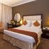 Flora Park Deluxe Hotel Apartments in Dubai guest room with king bed, desk, mirror and armchair