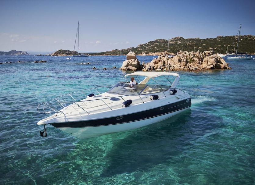 Aethos Sardinia in Cannigione, yacht floating in clear turquoise water near rocky coastline