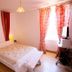 Logis Auberge La Cremaillere in Villandraut bedroom with bed, red curtains and bright window