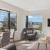 110 Hampden Apartments Hobart living room with city and water views, wall-mounted TV and armchairs