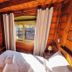 Pousada Charm Canela room in Canela with wood-paneled walls, TV, bed, and window with curtains
