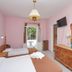 Dolphin Hotel Skopelos twin room with pink walls, wooden furniture, wall-mounted TV and balcony view