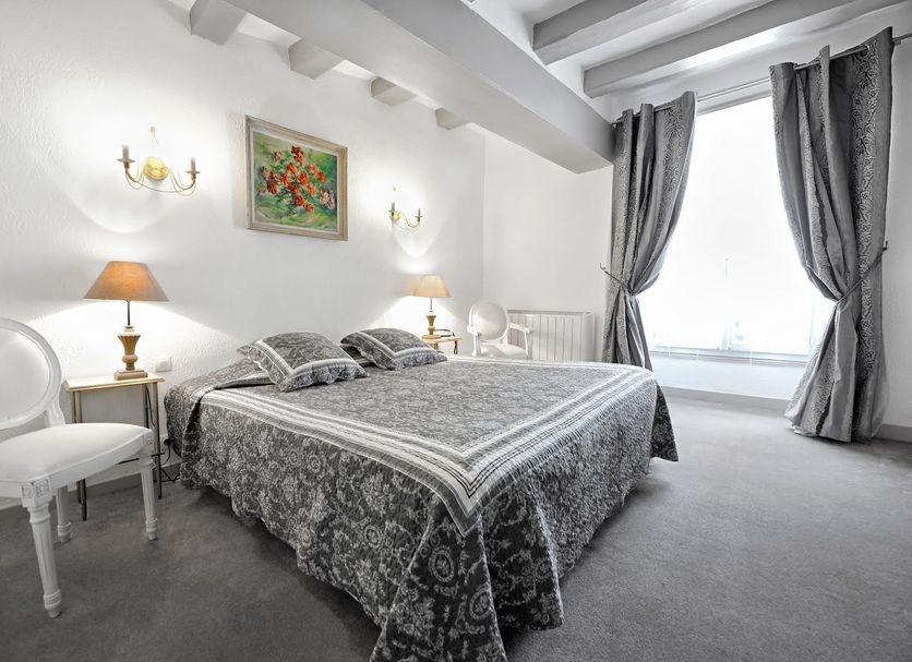 Hotel La Roseraie in Chenonceaux bedroom with ornate bed, twin lamps and window with gray curtains