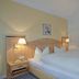 Gästehaus Achental in Berchtesgaden bedroom with double bed, bedside lamps and window with red curtains