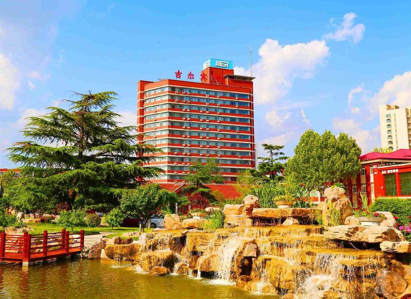 Jinan Jier Hotel in Jinan with a red high-rise, landscaped gardens, and waterfall pond