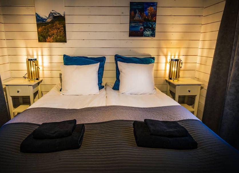 Arctic Gourmet Cabin in Kiruna: cozy double bed with bedside lamps and wall art
