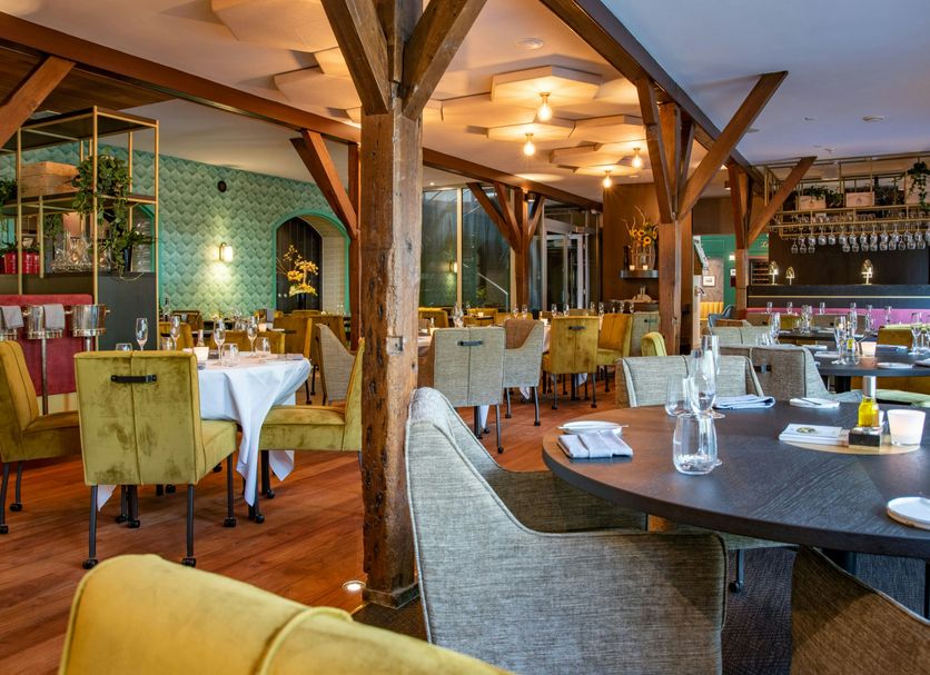 Hotel & Spa Savarin in Rijswijk restaurant with timber beams, set dining tables, and warm lighting