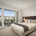 Quest Sanctuary Lakes in Melbourne: bright bedroom with king bed and balcony overlooking townhouses