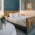 The Coal Exchange Hotel Cardiff guest room with carved wood bed, teal tufted headboard and round mirror
