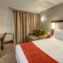 StayEasy Pretoria guest room with double bed, sofa chair, desk, and curtains