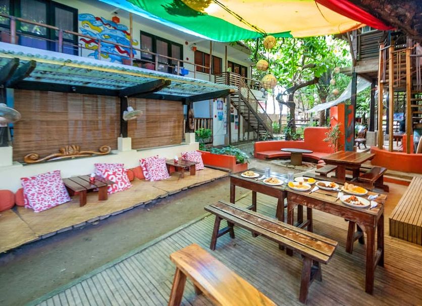 Lazy Dog Bed & Breakfast in Boracay courtyard dining area with wooden tables, benches, and colorful shade canopy
