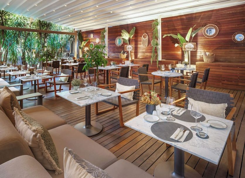 Meliá Lebreros in Seville hotel restaurant with wood deck, indoor-outdoor seating and lush greenery