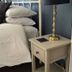 The Green Man in Rugby: bed with stacked pillows, bedside table and brass lamp in a guest room.
