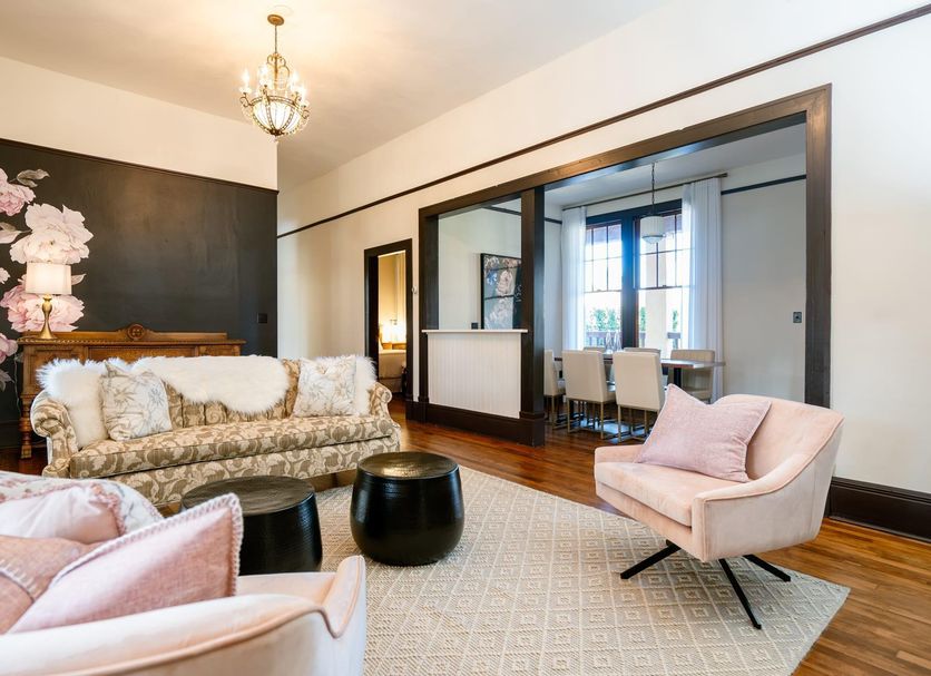 Naramata Inn guest lounge with floral accent wall, pink chairs, dark wood floors and dining nook