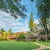 Lombok Garden Hotel in Mataram with a lush garden lawn, palm trees, and blue sky